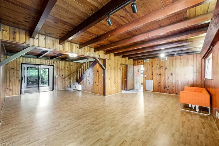 Unfurnished living room with light wood-type flooring, wooden ceiling, and wooden walls