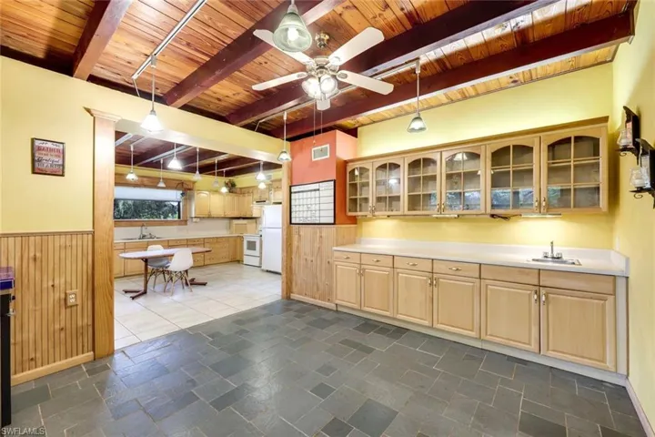 Wet-bar in Dinning Area with light brown cabinetry, decorative light fixtures, beamed ceiling, and ceiling fan