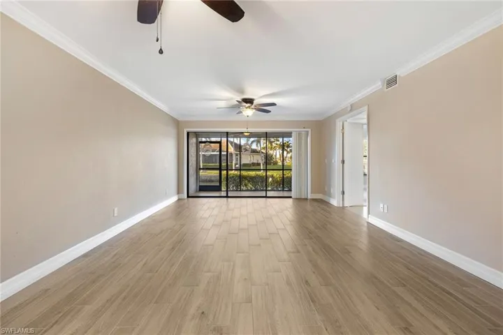 Living room with crown molding, light wood-style floors, and a ceiling fan