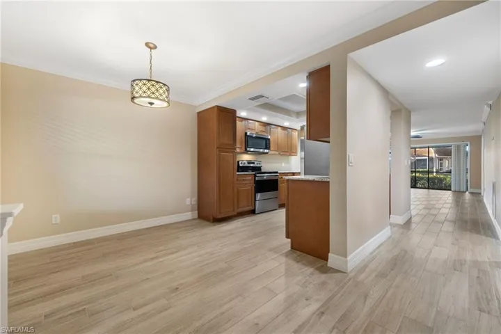Kitchen with brown cabinets, stainless steel appliances, light wood-style flooring, recessed lighting, and pendant lighting