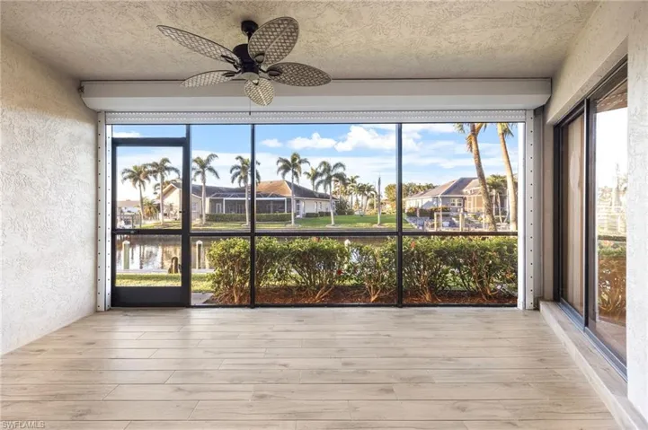 Unfurnished sunroom/patio with wood finished floors, a textured wall, a water view, and a textured ceiling