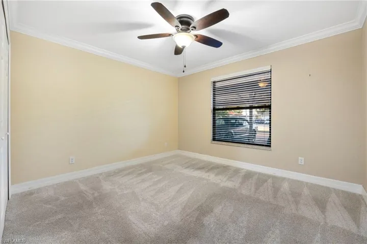 Carpeted spare room with ornamental molding and a ceiling fan