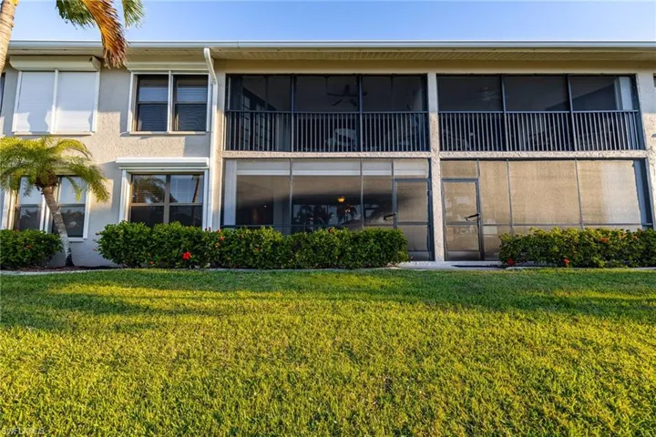 Back of property with a sunroom, stucco siding, and a yard