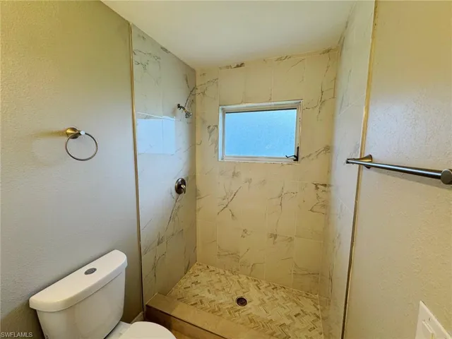 Bathroom featuring a tile shower and toilet
