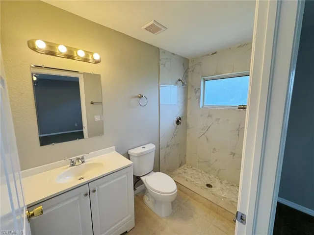 Bathroom with vanity, toilet, and tiled shower