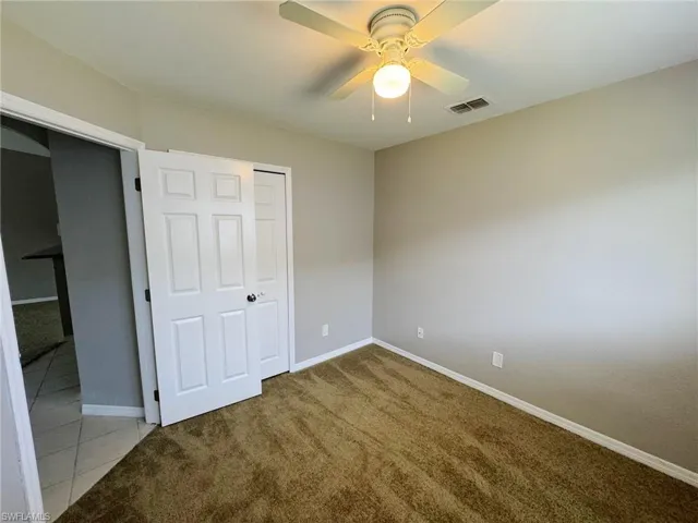 Unfurnished bedroom with ceiling fan, light colored carpet, and a closet