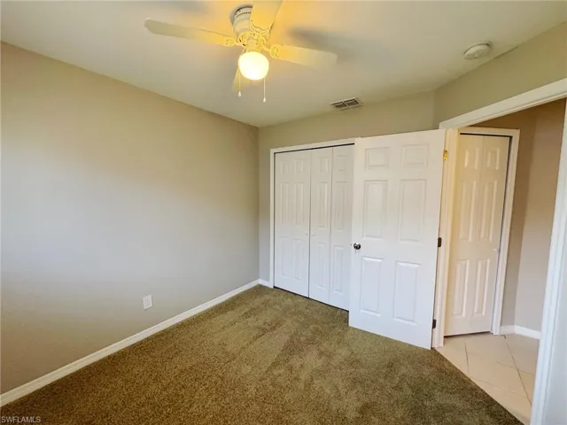 Unfurnished bedroom featuring ceiling fan, a closet, and light carpet