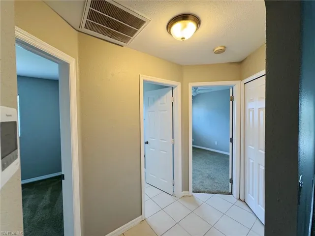 Corridor with light tile patterned floors and a textured ceiling