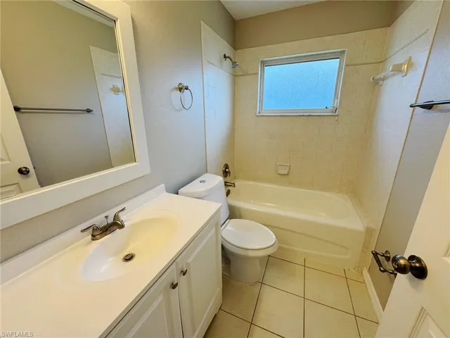 Full bathroom with toilet, tile patterned flooring, vanity, and tiled shower / bath