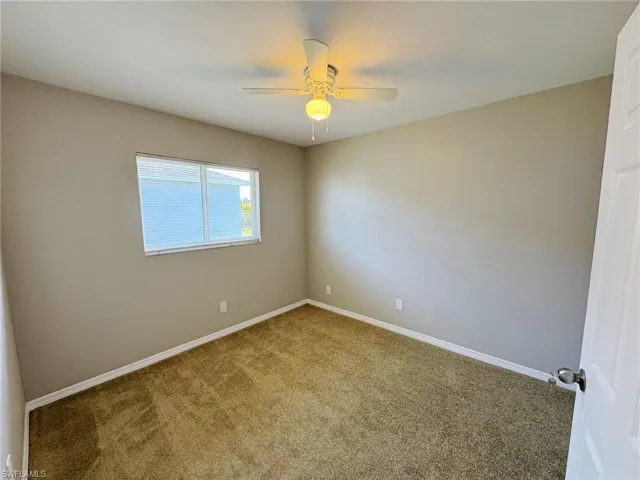 Carpeted spare room featuring ceiling fan