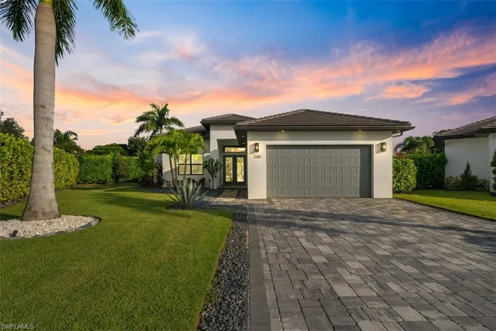 View of the front of the home with pavers, rock, and beautiful landscape.