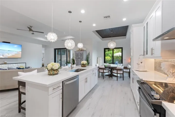 Kitchen featuring pendant lighting, sink, white cabinets, stainless steel appliances.