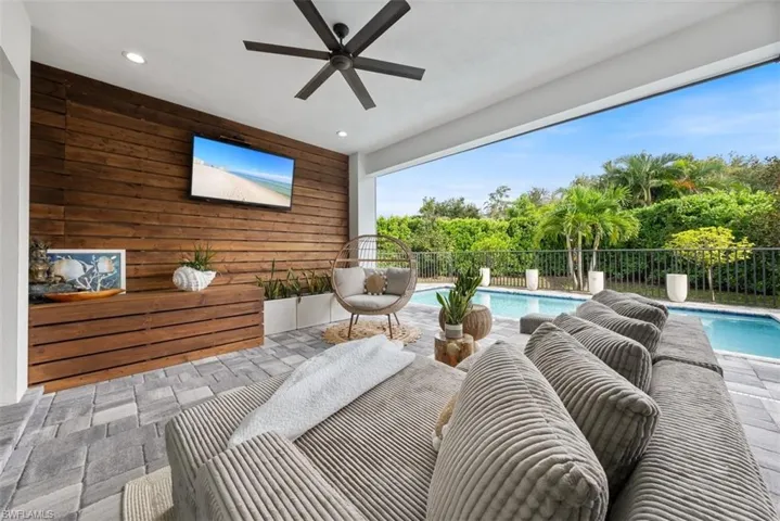 View of patio with a large covered area, beautiful wood feature wall and electric screens to keep the bugs out.