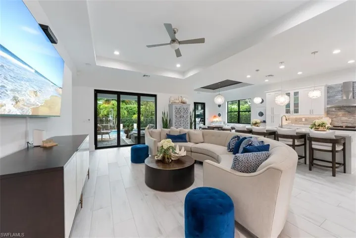 Great room featuring ceiling fan, porcelain tile and a tray ceiling.