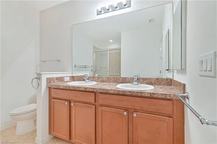 Bathroom featuring a shower stall, double vanity, and tile patterned floors