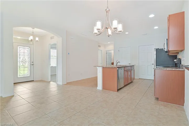 Kitchen with appliances with stainless steel finishes, arched walkways, a chandelier, an island with sink, and recessed lighting