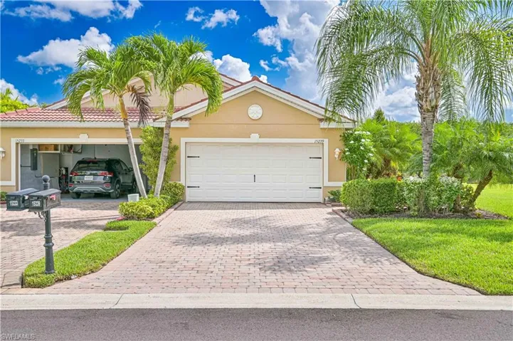 View of front of house with stucco siding, an attached garage, decorative driveway, and a front lawn