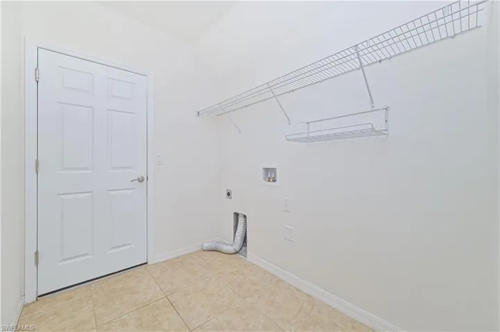 Washroom featuring hookup for an electric dryer, hookup for a washing machine, and light tile patterned floors