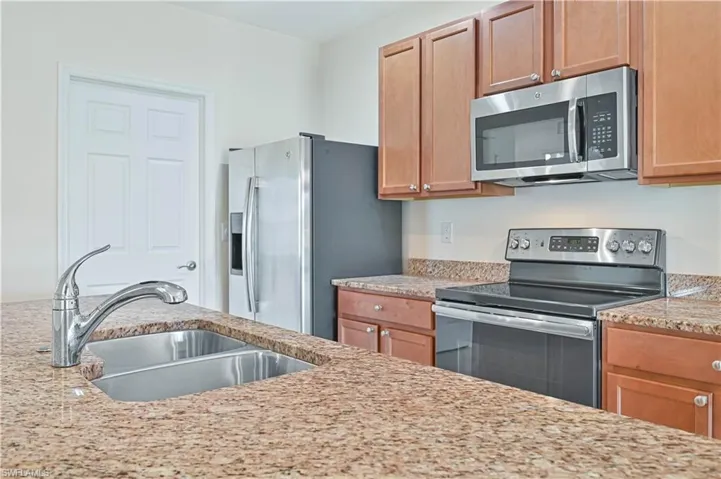 Kitchen featuring appliances with stainless steel finishes and light stone countertops