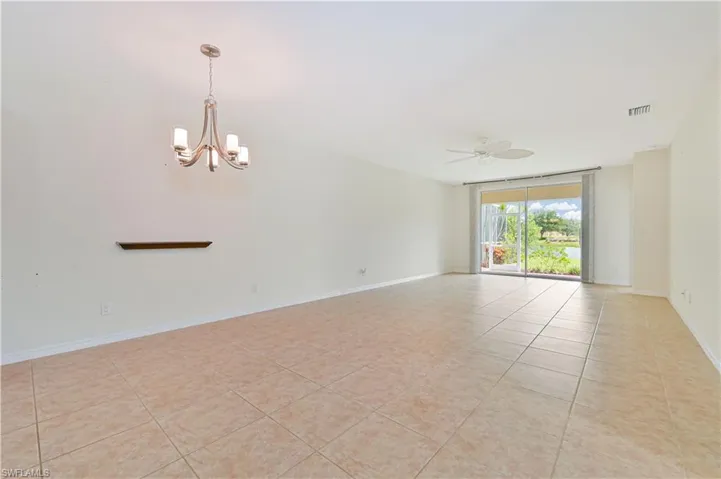 Spare room with a chandelier, light tile patterned floors, and a ceiling fan