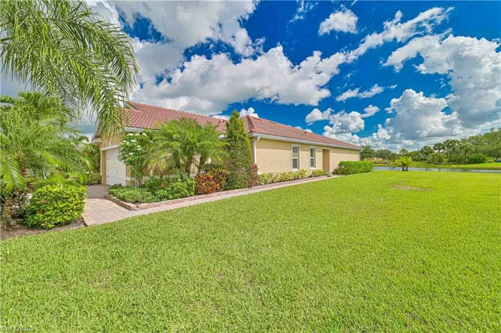 View of side of home with stucco siding, a water view, a tiled roof, and a yard