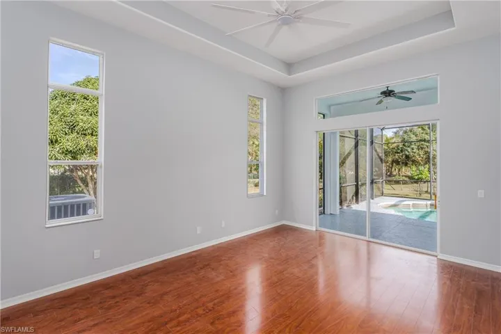 Unfurnished room with a raised ceiling, hardwood / wood-style floors, ceiling fan, and a sunroom