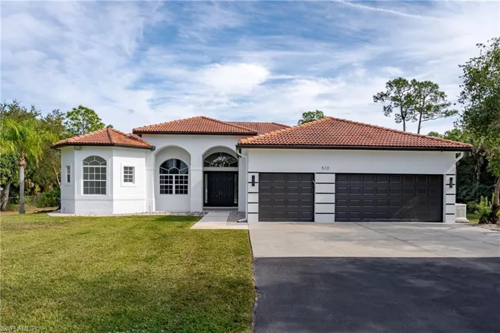 Mediterranean / spanish-style house with concrete driveway, a front yard, an attached garage, and a tile roof