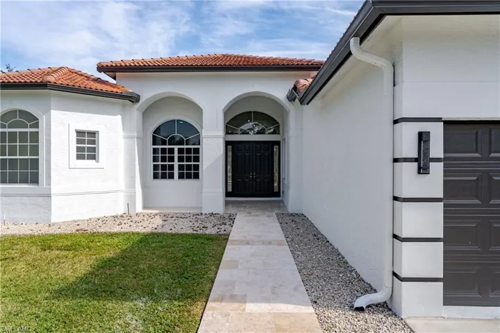 View of exterior entry featuring stucco siding, a yard, and a tile roof