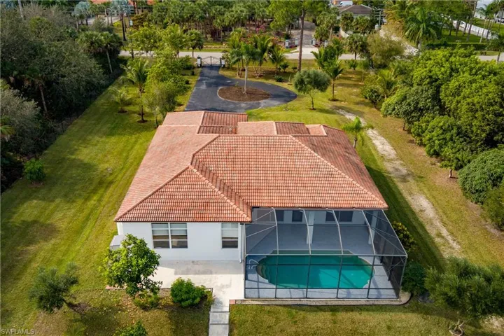 View from above of property with a pool area and a tree filled landscape