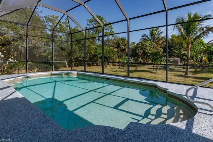 Swimming pool with glass enclosure, a sunroom, a lawn, and a patio