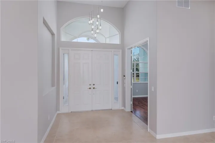 Foyer entrance with a towering ceiling, a chandelier, and light tile patterned floors