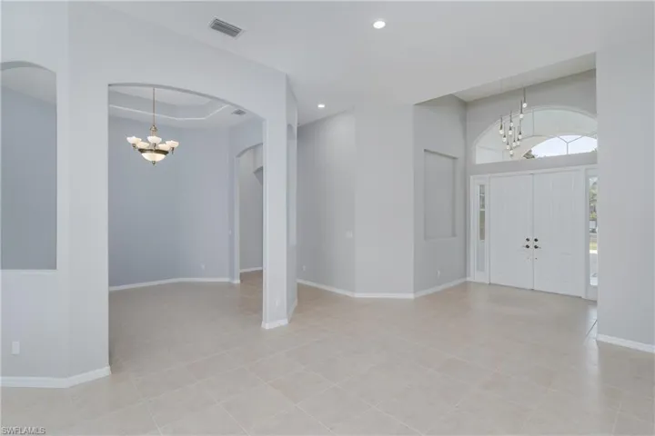 Entryway with a chandelier, arched walkways, recessed lighting, and light tile patterned flooring