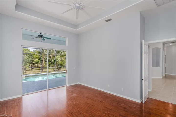 Empty room featuring a tray ceiling, wood finished floors, a ceiling fan, and a high ceiling