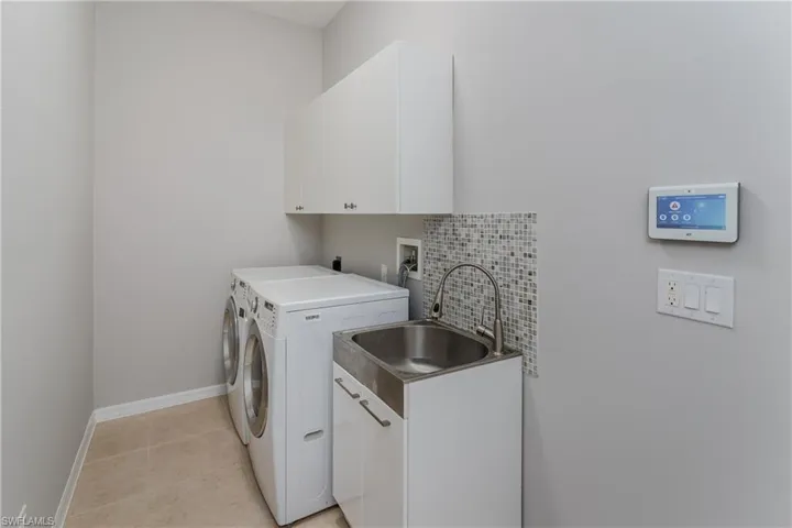Laundry room with cabinet space, light tile patterned flooring, and washing machine and dryer