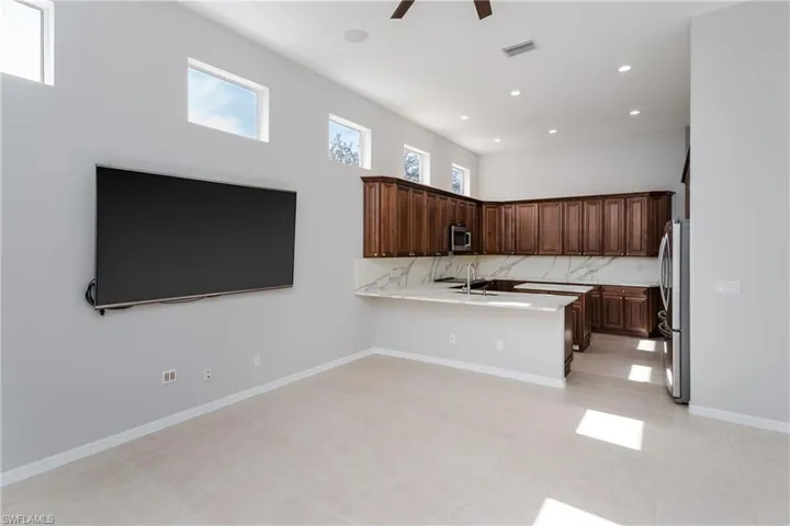 Kitchen featuring dark brown cabinets, decorative backsplash, recessed lighting, stainless steel appliances, and a peninsula