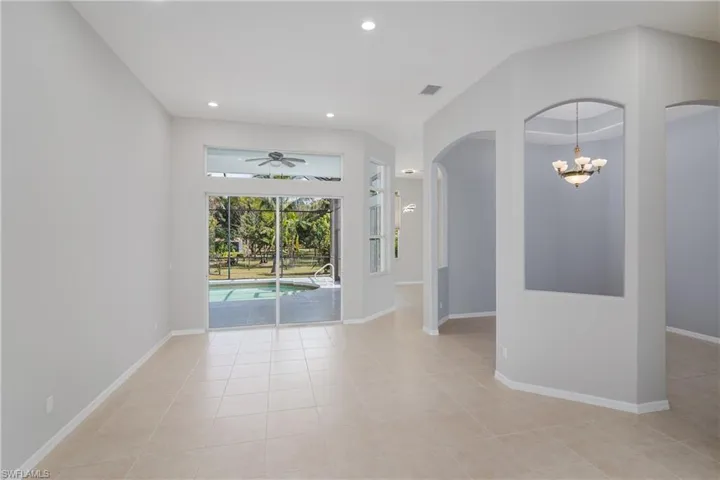 Empty room with a chandelier, arched walkways, light tile patterned floors, a ceiling fan, and recessed lighting