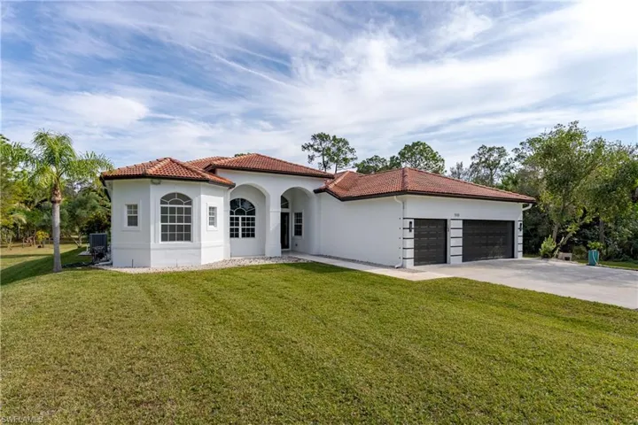 Mediterranean / spanish-style home featuring a front lawn, driveway, a tiled roof, stucco siding, and an attached garage