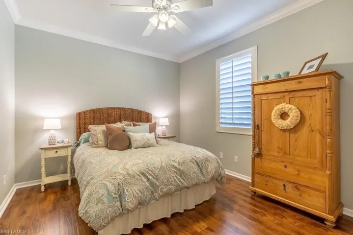 Bedroom with dark hardwood / wood-style floors, ceiling fan, and crown molding