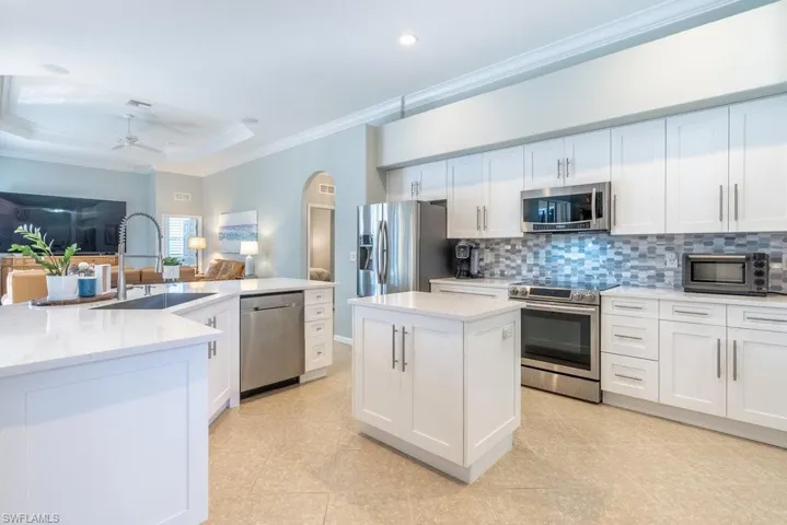 Kitchen featuring a kitchen island with sink, sink, white cabinets, and stainless steel appliances