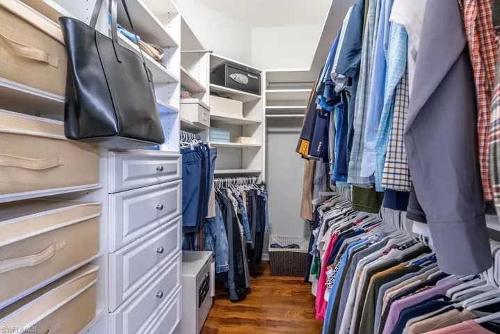 Walk in closet with dark hardwood / wood-style flooring