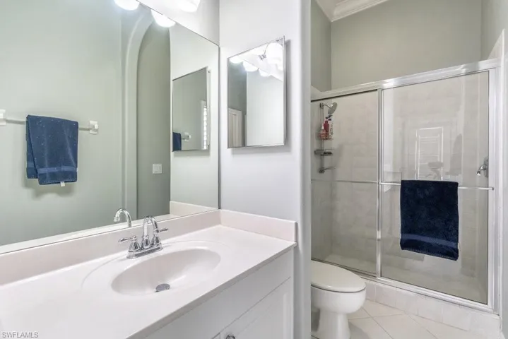 Bathroom with toilet, vanity, tile patterned floors, and a shower with door