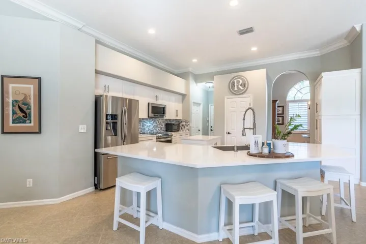 Kitchen featuring a spacious island, white cabinetry, and stainless steel appliances