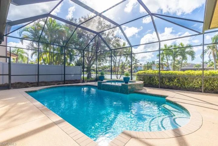 View of pool featuring glass enclosure, an in ground hot tub, and a patio area