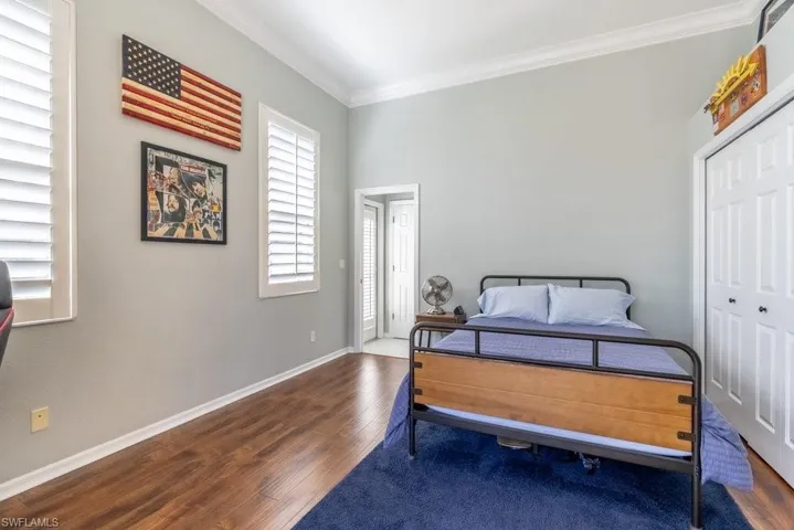 Bedroom featuring crown molding, a closet, and dark wood-type flooring