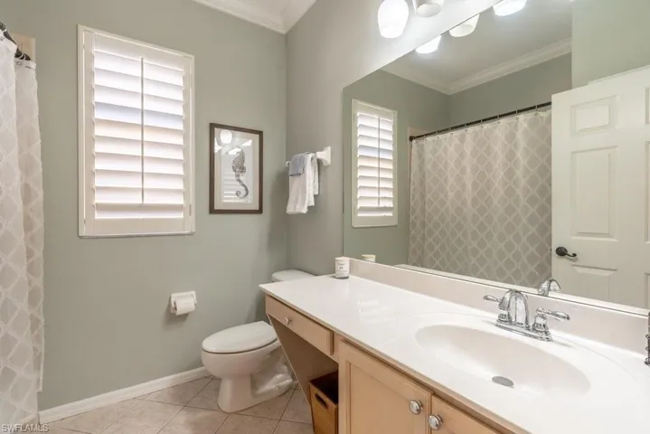 Bathroom with a wealth of natural light, crown molding, vanity, and tile patterned flooring