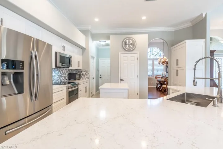 Kitchen featuring ornamental molding, sink, appliances with stainless steel finishes, dark hardwood / wood-style flooring, and light stone counters