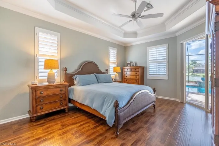 Bedroom featuring dark hardwood / wood-style flooring, multiple windows, ornamental molding, and ceiling fan