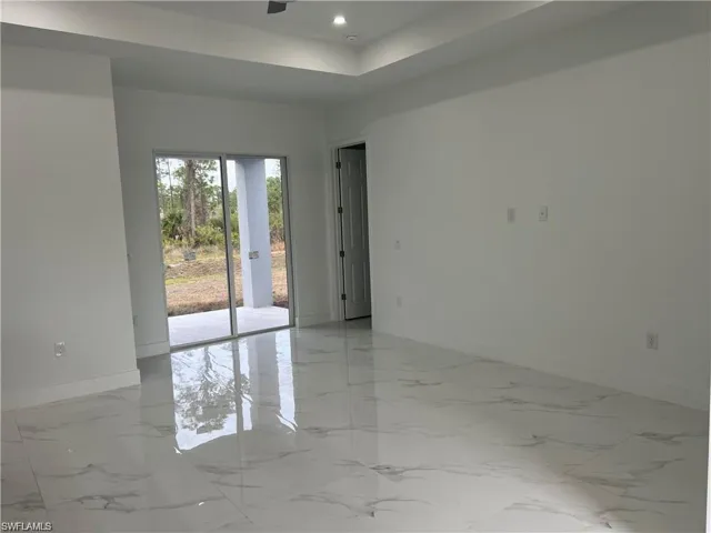 Tiled empty room featuring a raised ceiling