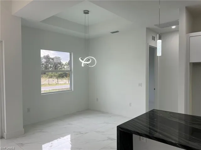 Unfurnished dining area with a raised ceiling and light tile patterned floors