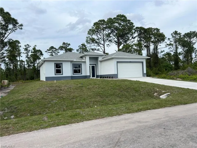 View of front facade featuring a garage and a front lawn